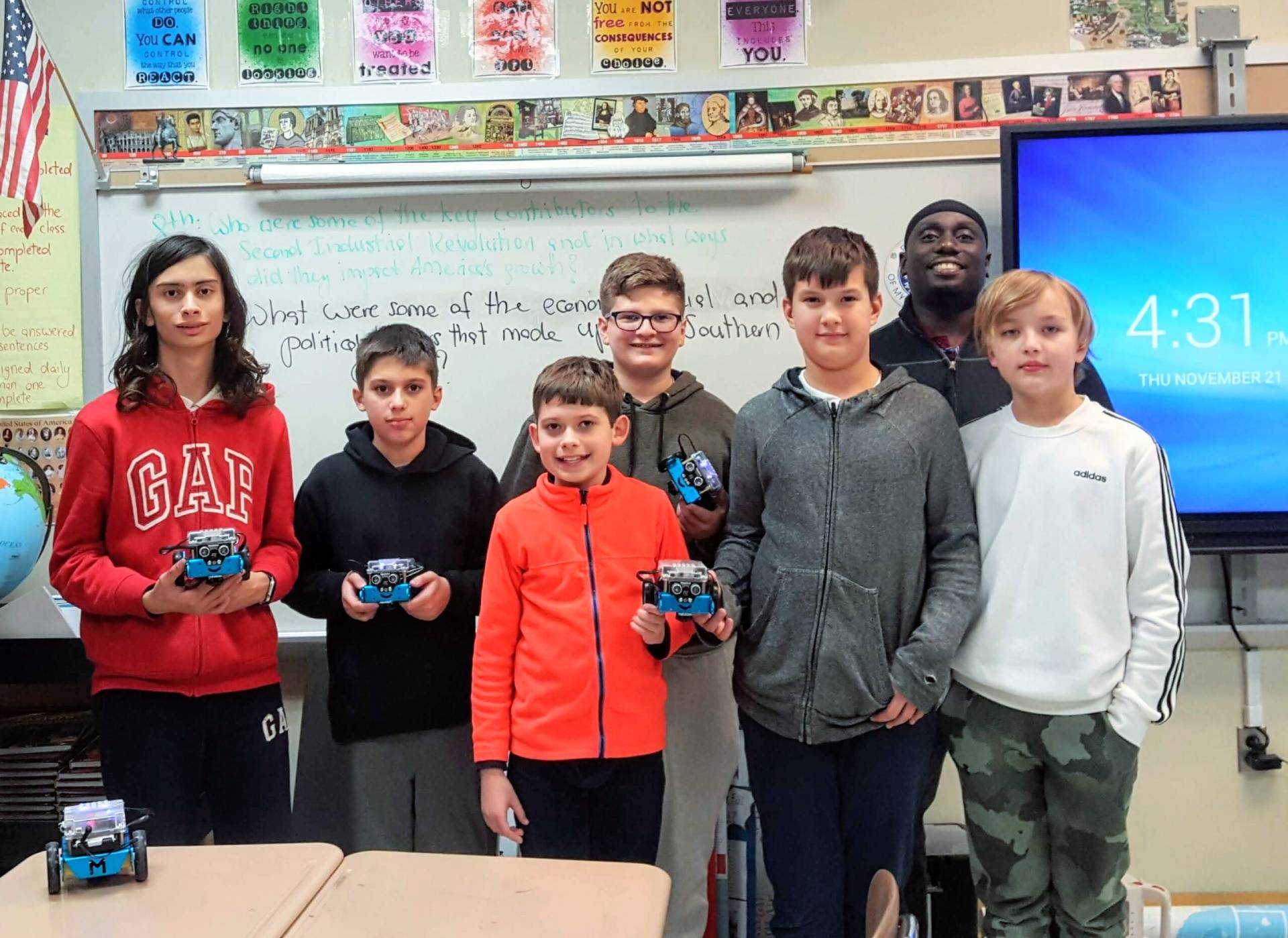 Five middle school students show their built robots with their instructor during after school program.