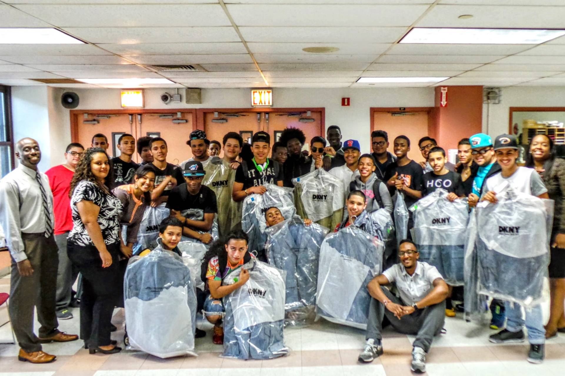 Large group photo for Dress For Success event with high school boys receiving a new sport coat from DKNY.